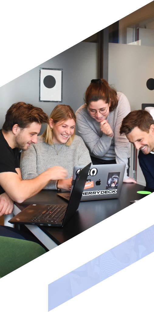 Four colleagues gathered around a laptop, are sharing cheerful moments