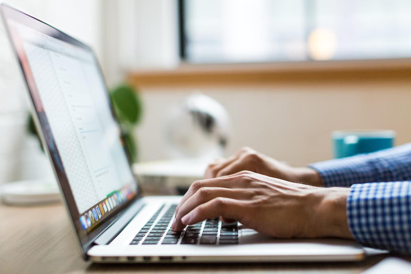 A person's hands typing on a laptop, symbolizing the challenges faced by the visually impaired with inadequate web accessibility widgets.