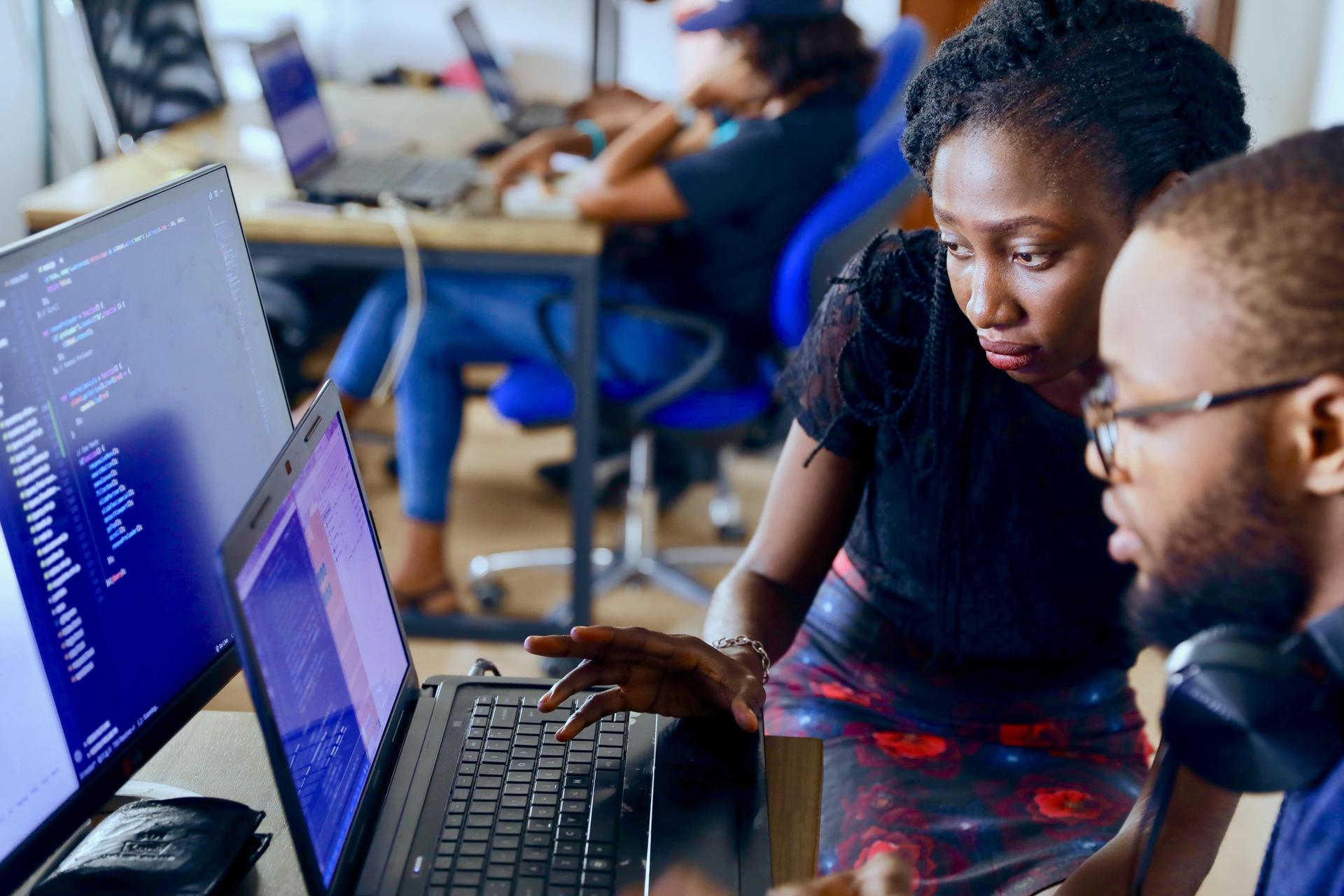 Two developers discussing code on a computer screen, representing the importance of ADA compliance in web development.