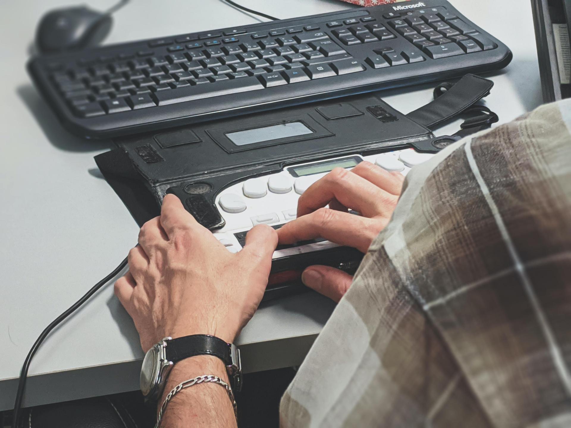 Close-up of hands using an accessible keyboard, emphasizing the importance of web accessibility features.