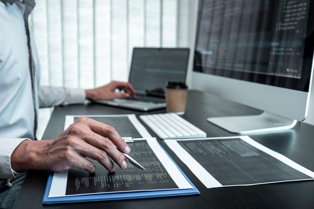 a man is sitting in front of computers examining reports