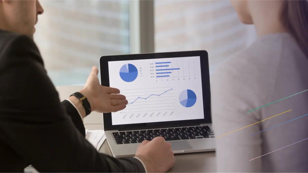 Two individual are examining the statistic charts displayed on a laptop