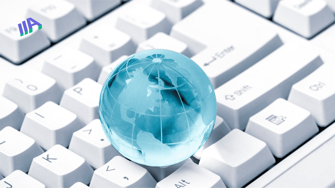 A light blue translucent globe with map outlines is placed on a white computer keyboard. 