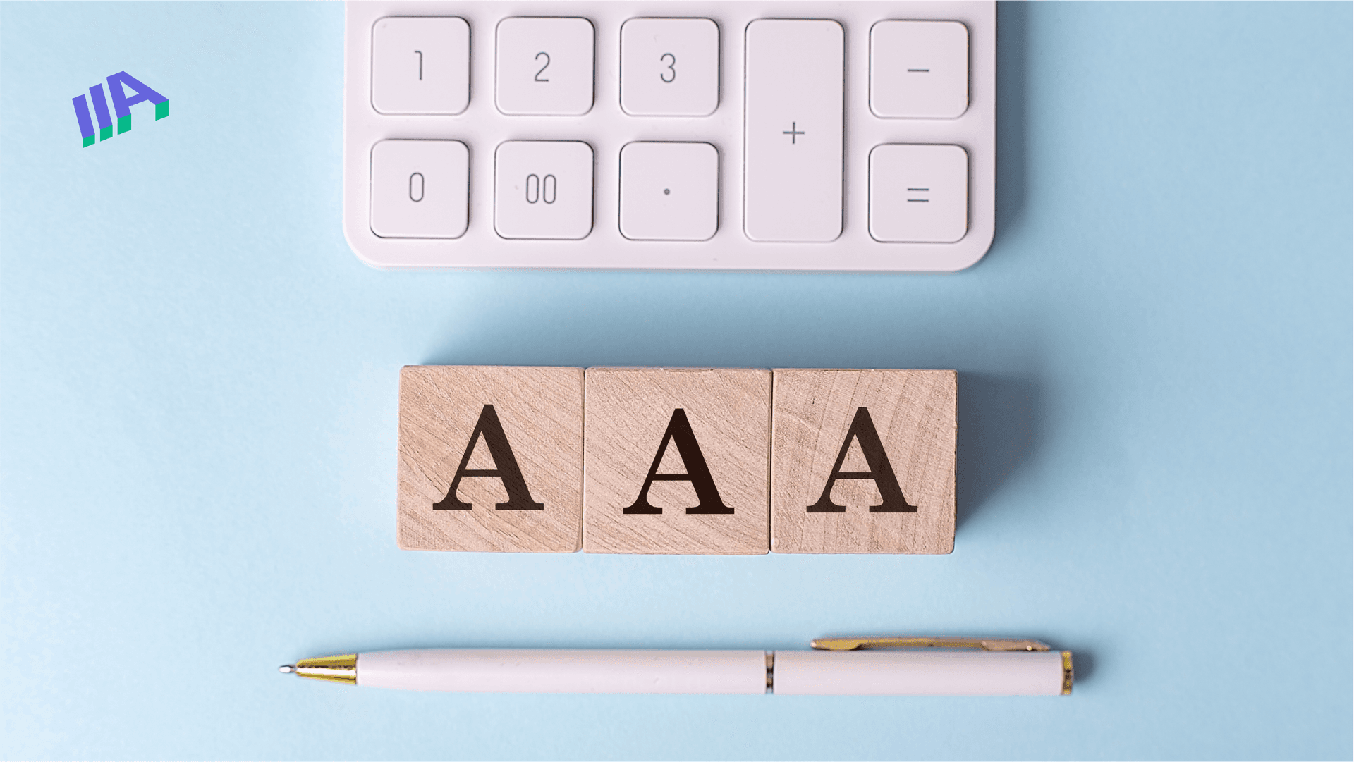 Three wooden blocks, each with the letter "A" printed on them, aligned in a row. Above the blocks, a white calculator keypad is visible, and below the blocks, a white pen with a gold accent is positioned horizontally.